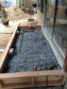 Back porch ready for the pour. Can you see the masonry detritus poking through the gravel? Also a good look at the forms and reinforcement for the can lights.