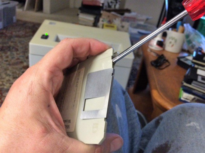 Pry the disk cover open by inserting a screwdriver near the metal slide.